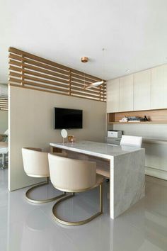 a modern kitchen with marble counter tops and white chairs, along with a flat screen tv mounted on the wall