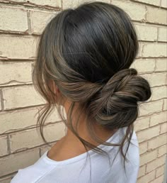 a woman's hair in a low bun is shown from the back, with dark brown highlights