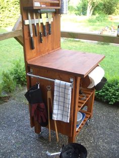 an outdoor kitchen with utensils hanging from it's cabinet and rack on the outside