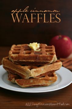 a stack of waffles on a white plate with an apple in the background