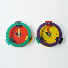 two colorful clocks are on the wall next to each other