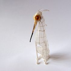 a glass bird with an orange eye on it's head and neck, standing upright