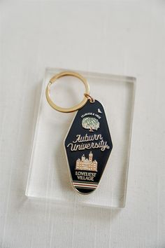 a black and gold keychain with the words auburn university on it is sitting on a white surface