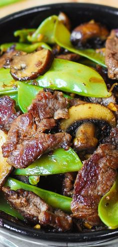 beef and mushrooms stir - fry in a wok with green peppers on the side