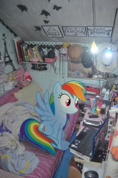 a bed room with a laptop computer on top of it and a rainbow pony in the corner