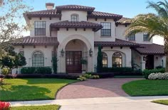 a large house with lots of windows and palm trees in the front yard, surrounded by greenery