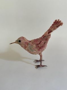 a bird made out of fabric sitting on top of a white surface