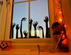 a window with halloween decorations in front of it and hands coming out from the windowsill