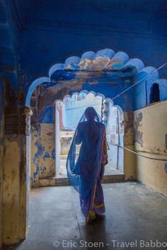 a woman in a blue sari walking through an archway