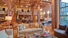 a living room filled with furniture next to a large open floor plan and lots of windows