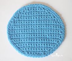 a crocheted blue circle on a white surface with the bottom half covered in yarn