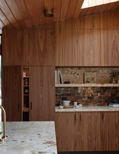 a kitchen with wood paneling and marble counter tops, along with an island in the middle