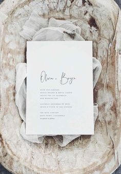 a white wedding card sitting on top of a wooden plate