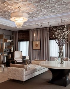 a living room filled with furniture and a chandelier above a round dining table