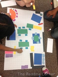 two children sitting on the floor working with construction paper