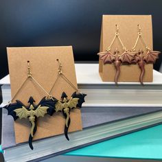 two dragon earrings are sitting on top of a book