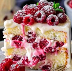 a piece of cake with white frosting and raspberries on top