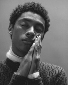 a black and white photo of a young man holding his hands to his face with both hands