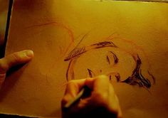 someone is drawing a woman's face on a piece of paper