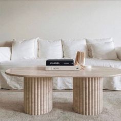 a white couch sitting next to a table with a book on top of it in front of a sofa