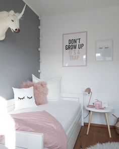 a white bed sitting in a bedroom next to a wall mounted unicorn head on the wall