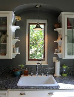 a kitchen sink sitting under a window next to white cabinets