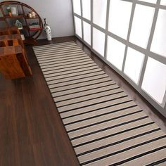 a room with wood floors and white walls, along with a rug on the floor