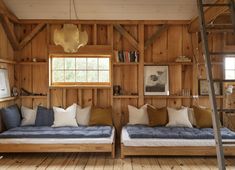 two beds in a wood paneled room with ladders to the ceiling and windows