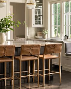 a kitchen island with three stools and a potted plant