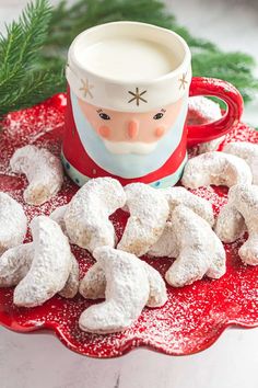 a red plate topped with snow covered cookies next to a cup