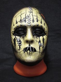 a yellow mask with black and white paint on it