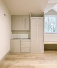 an empty kitchen with white cabinets and wood flooring in the room that has no windows