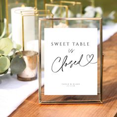 a sign that says sweet table in cursive writing on it next to some candles