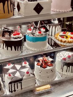 many different cakes are on display in a glass case with black, white and red decorations