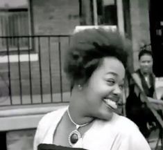 a black and white photo of a woman laughing in front of a man on the street