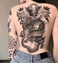 the back of a woman's body with tattoos on her chest and dragon tattoo