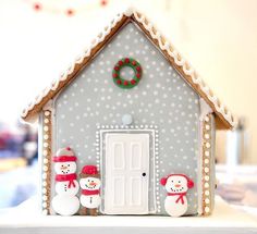 a gingerbread house with snowmen and a wreath on the door