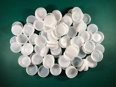 a pile of white dishes sitting on top of a green table