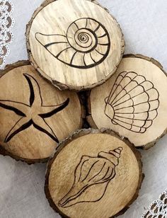 four wood slices with designs on them sitting on a doily covered tablecloth,