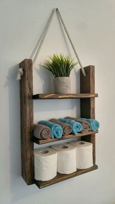 a wooden shelf with several rolls of toilet paper hanging from it's sides and a potted plant on top