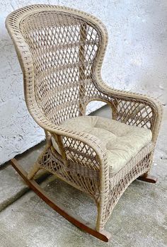 a wicker rocking chair with cushion on concrete floor