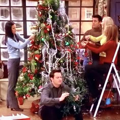 the friends are decorating the christmas tree together