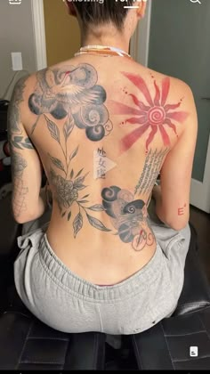 a woman with tattoos on her back sitting down