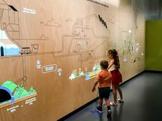 two children standing in front of a wall with drawings on it