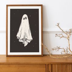 a black and white drawing of a ghost hanging on a wall next to a plant