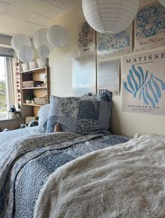 a bed room with a neatly made bed and lots of pictures on the wall above it