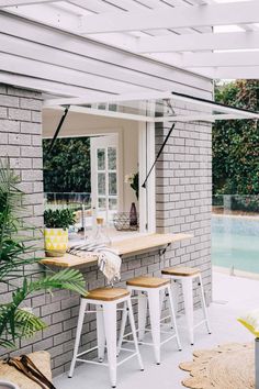 an outdoor bar with stools next to a pool