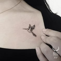 a woman's chest with a small bird tattoo on the left side of her neck