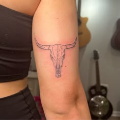 a woman's arm with a tattoo of a bull skull on the left side