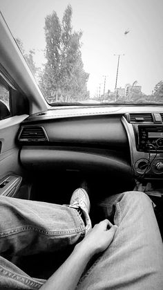 a person sitting in the driver's seat of a car with their feet on the dashboard